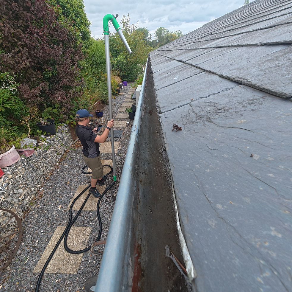 Gutter clearing pole working along a slate roof in Hampshire