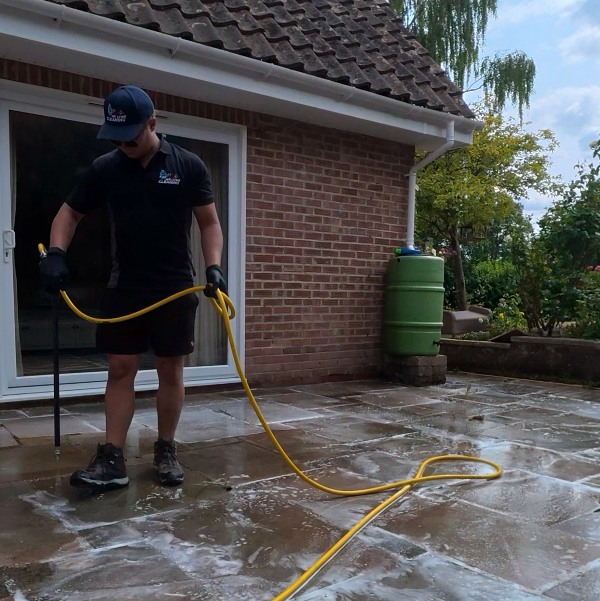 We Love Cleaning technician applying a specialist soft-wash treatment to a patio